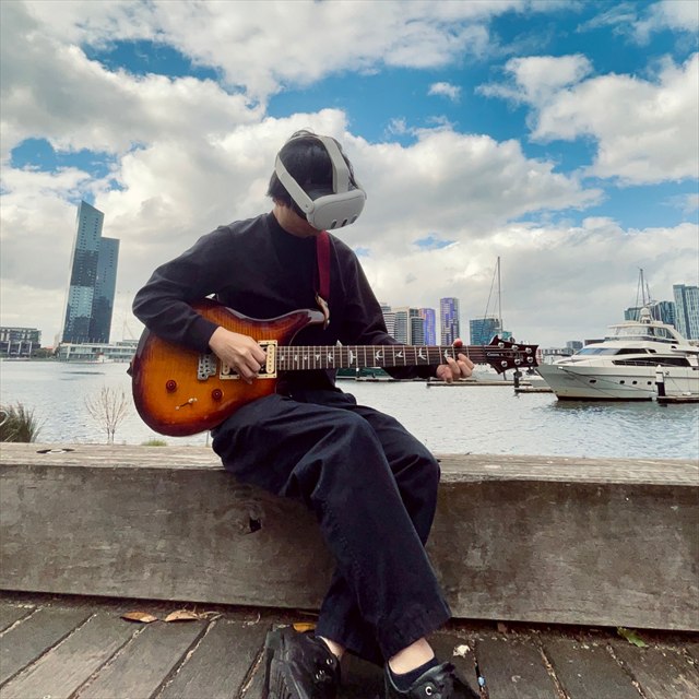 HMD を装着して屋外でギターを演奏するメンバー