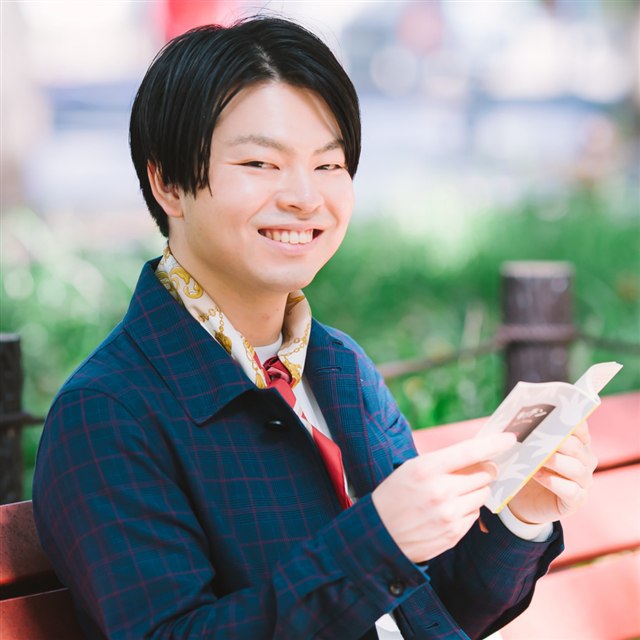 屋外のベンチで本を開くメンバーのポートレート